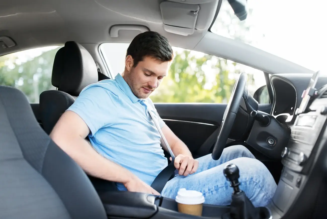 Driver reaching for the seat belt buckle before starting a journey in a passenger car