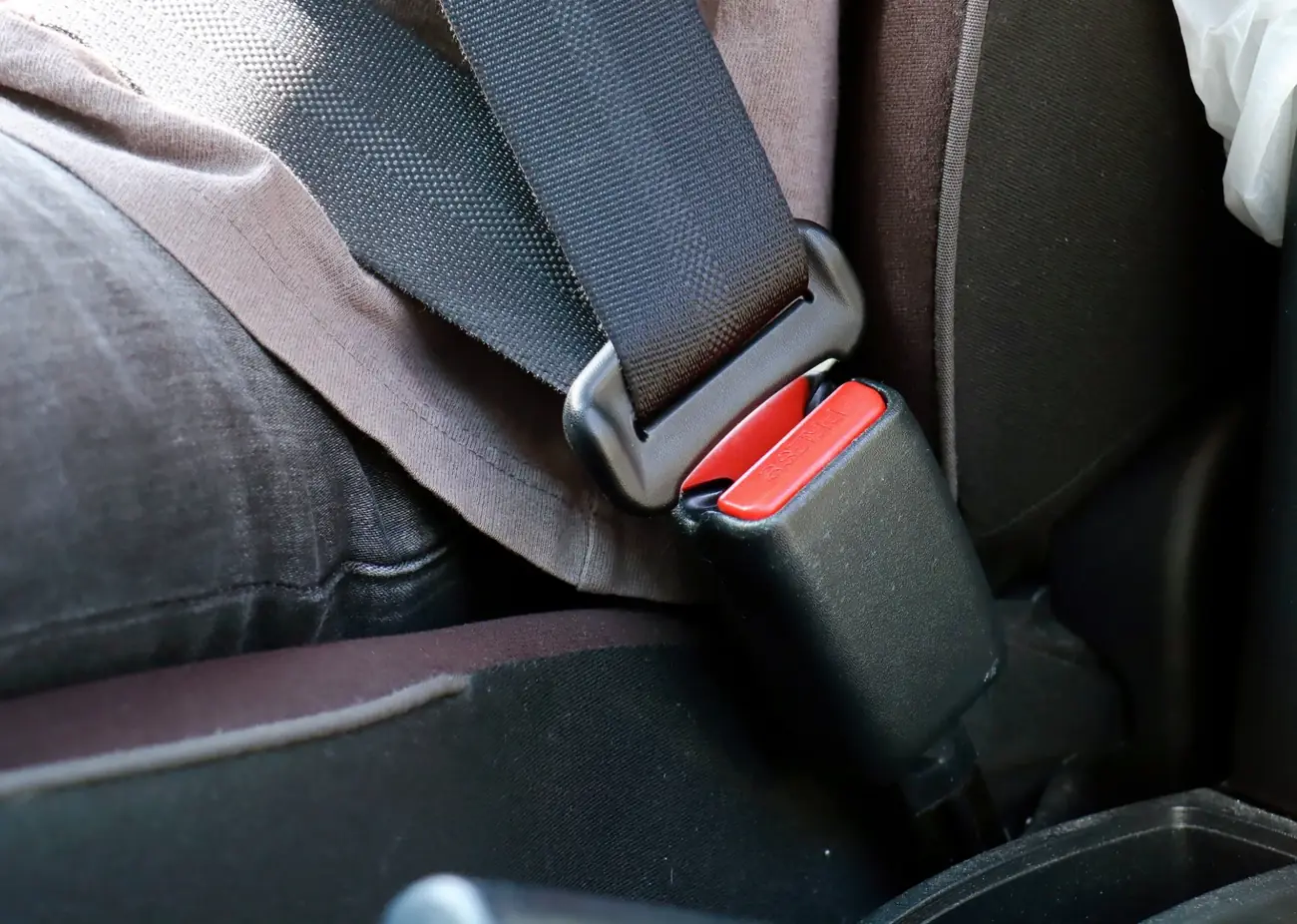 Metal seat belt latch plate held against the buckle housing inside a vehicle cabin