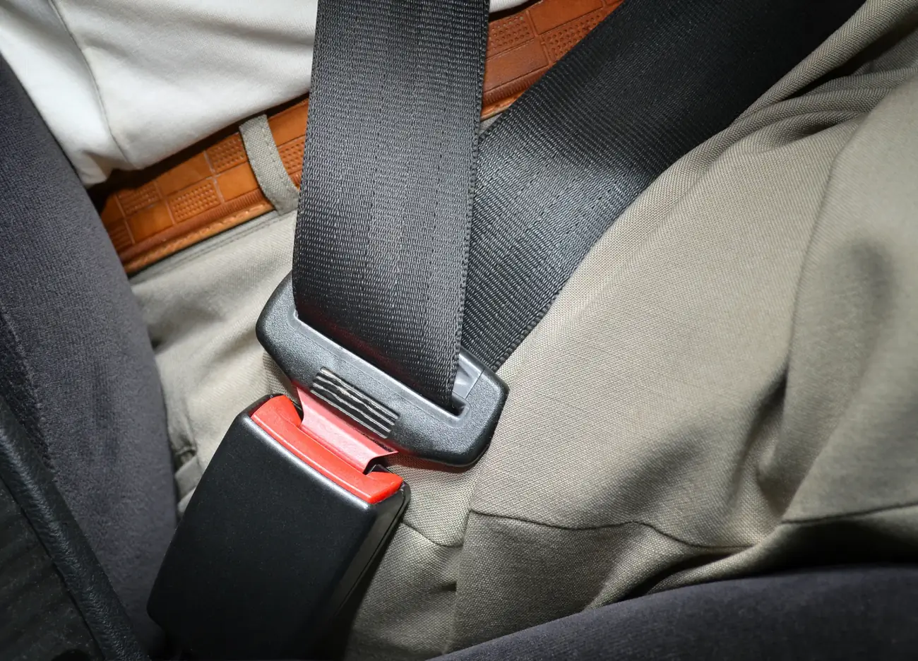 Seat belt webbing running from the shoulder into a latched buckle across an occupant's lap