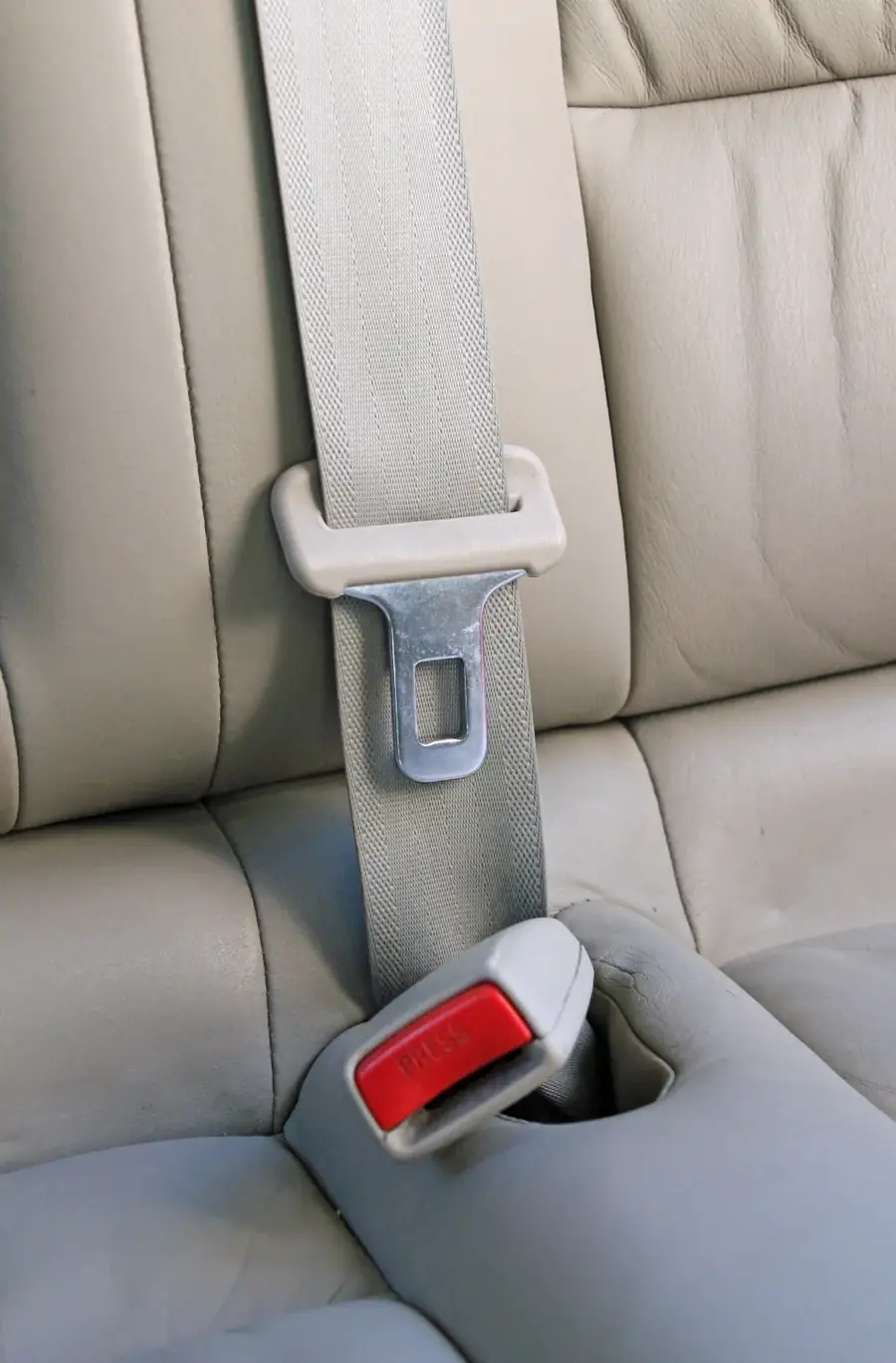 Seat belt passing through a height adjuster loop with the latch plate and release buckle visible below