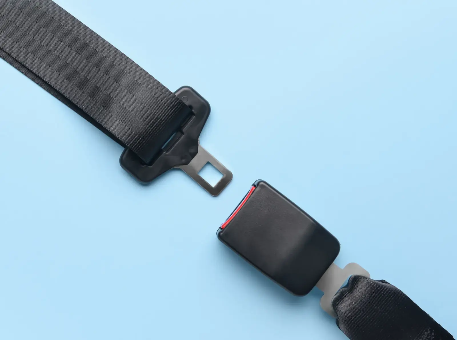 Automotive seat belt assembly laid out flat showing the webbing, latch plate and buckle housing separated